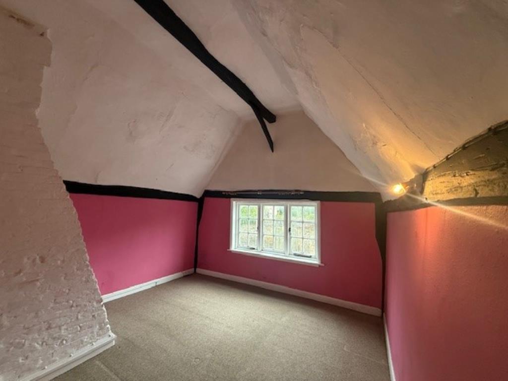 Lot: 115 - A PAIR OF THATCHED COTTAGES IN NEED OF IMPROVEMENT - 50 Abbey Street main bedroom with window and vaulted ceiling